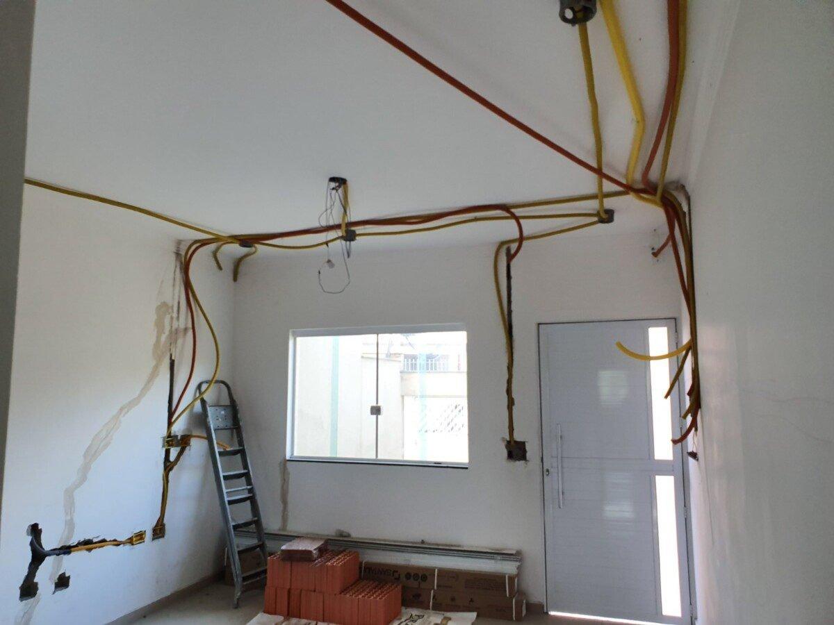 Sala em obra com eletrodutos amarelos presos ao teto