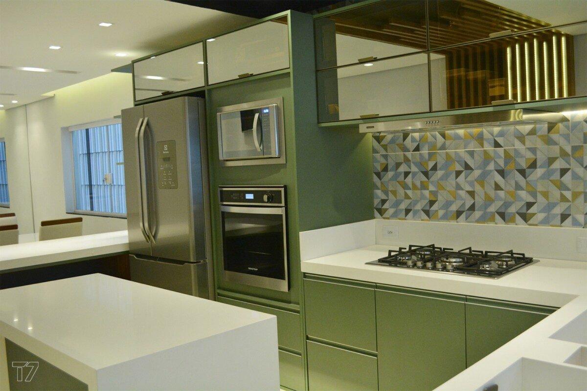 Cozinha com cooktop, revestimento geométrico e armários verdes
