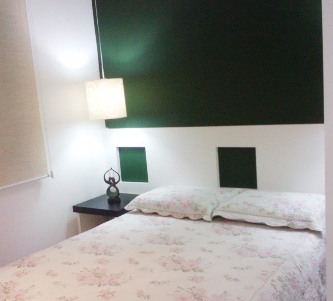 Quarto pronto com painel verde atrás da cama