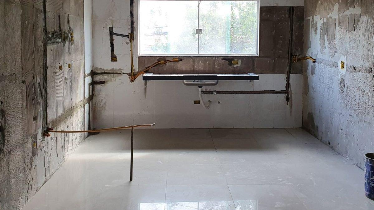Antes: Cozinha em obra, com tubulações e pontos de água expostos na parede