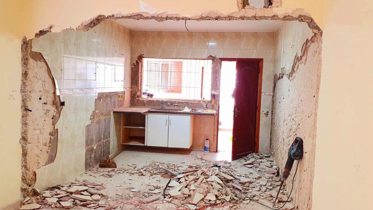 Antes: Parede da cozinha sendo demolida, com entulho no piso