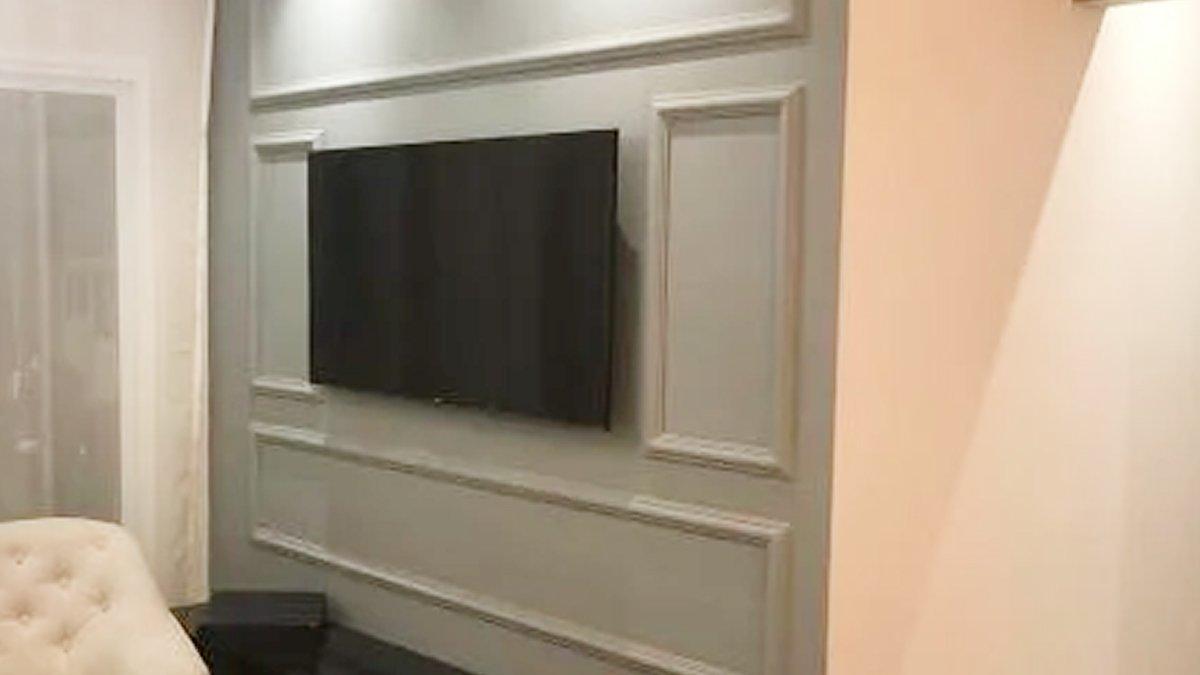 Depois: Parede com molduras pintadas e televisão instalada